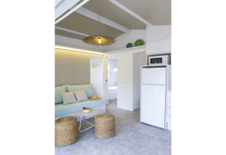Moderne opholdsstue i Tamarit Park Resort 1 THALASSA med sofa, fletskamler og tekøkken, Spanien.