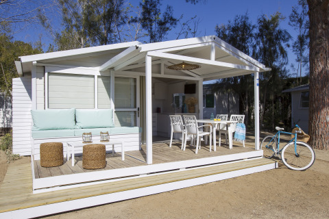 Wit chalet met overdekte veranda, zitgedeelte en fiets bij Tamarit Park Resort 1 THALASSA in Spanje.