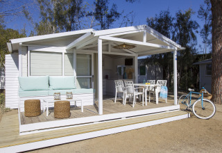 Wit chalet met overdekte veranda, zitgedeelte en fiets bij Tamarit Park Resort 1 THALASSA in Spanje.