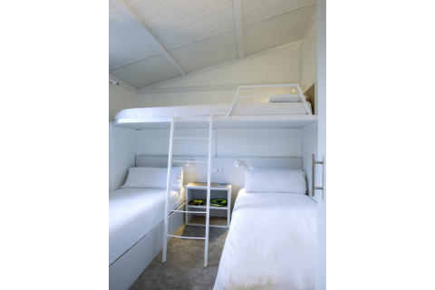 Et lyst og moderne soveværelse med køjesenge og hvide vægge i Tamarit Park Resort 1 THALASSA, Spanien.