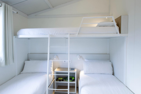 Moderne driepersoons stapelbed in Tamarit Park Resort 1 THALASSA, Spanje, met witte lakens en strak interieur.