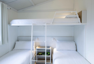 Moderne, lyst tre-personers køjeseng på chalet i Tamarit Park Resort 1 THALASSA, Spanien, med enkle møbler.