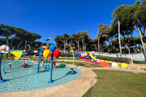 Børnevenligt vandland med farverige rutsjebaner og vandsprøjt, omgivet af træer ved Camping Interpals i Spanien.