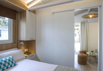 Camera da letto moderna con porta scorrevole verso il soggiorno in chalet al Tamarit Park Resort in Spagna.