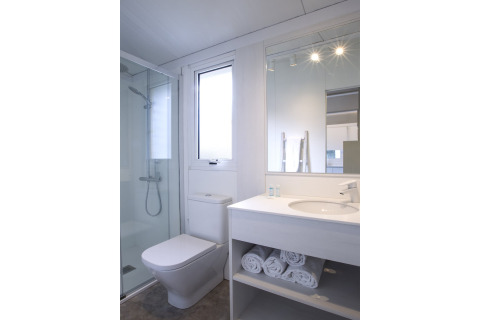Moderne badkamer in Tamarit Park Resort 1 THALASSA in Spanje, met douche, toilet en opgerolde handdoeken.