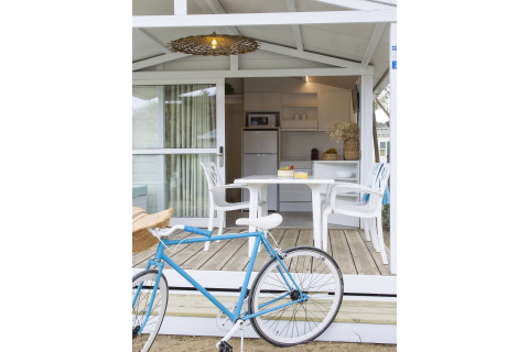Cykel foran terrasse med hvidt bord og stole, udsigt til køkken i chalet på Tamarit Park Resort, Spanien.