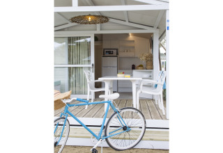 Fiets bij terras met witte tafel en stoelen, uitzicht op chaletkeuken in Tamarit Park Resort, Spanje.