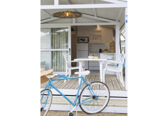 Bicicletta davanti a veranda con tavolo e sedie bianche, cucina dello chalet in Tamarit Park Resort, Spagna.