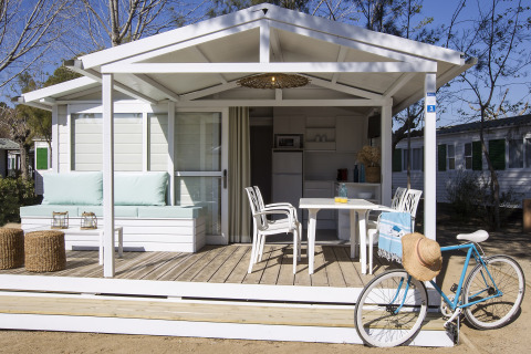 Hyggelig terrasse ved chalet Tamarit Park Resort 1 THALASSA i Spanien, med cykel og havemøbler i solskin.
