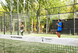 Deux personnes jouent au padel sur un terrain extérieur entouré d’arbres au Tamarit Beach Resort glamping.