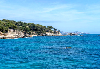 Paysage côtier depuis Camping Interpals- Bungalow Sa Riera en Espagne, avec falaises, mer bleue et verdure.