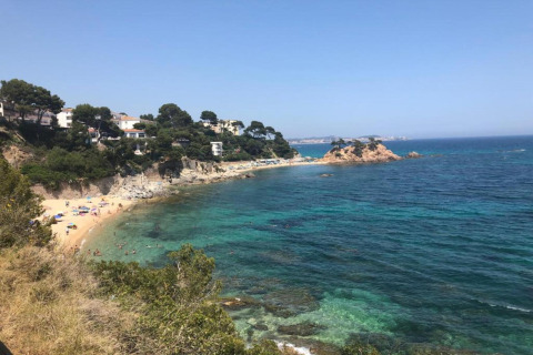 Udsigt over stranden og det klare blå hav ved Camping Interpals- Bungalow Sa Riera i Spanien.