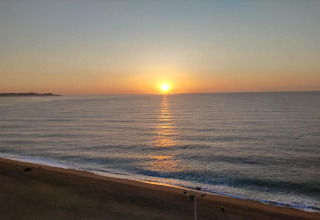 Solopgang over havet set fra Camping Interpals Bungalow Sa Riera i Spanien, med rolig strand og blødt lys.