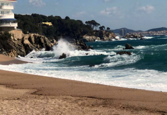 Vue sur la mer et les falaises rocheuses du Camping Interpals - Bungalow Sa Riera en Espagne, avec vagues et plage.