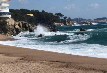Zicht op zee, branding en rotsen bij Camping Interpals - Bungalow Sa Riera in Spanje, met bomen aan het strand.