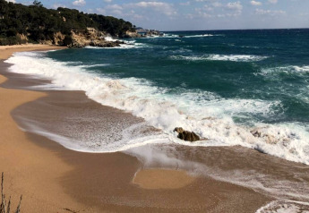 Plage à CAMPING INTERPALS- Bungalow Sa Riera en Espagne, avec vagues, rivage sablonneux et côte rocheuse.
