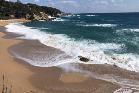 Strandbillede ved CAMPING INTERPALS- Bungalow Sa Riera med brusende bølger og klippefyldt kystlinje i Spanien.