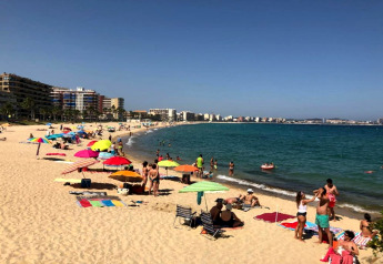 Scène de plage au Camping Interpals- Bungalow Sa Riera en Espagne avec gens, parasols et vue sur la mer.