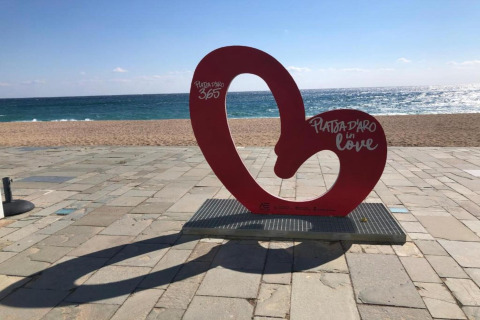 Rødt kunstværk på stranden ved Camping Interpals-Bungalow Sa Riera i Spanien med teksten Platja d’Aro.