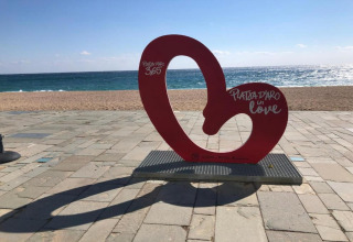 Rødt kunstværk på stranden ved Camping Interpals-Bungalow Sa Riera i Spanien med teksten Platja d’Aro.