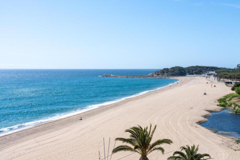 Smuk udsigt over den fredelige sandstrand og det blå hav ved Camping Interpals, Bungalow Sa Riera i Spanien.