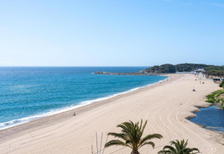 Smuk udsigt over den fredelige sandstrand og det blå hav ved Camping Interpals, Bungalow Sa Riera i Spanien.