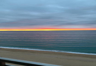 Solnedgangsudsigt over havet og stranden fra CAMPING INTERPALS-Bungalow Sa Riera, Spanien, med farverige skyer.