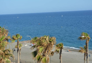 Udsigt over stranden og det blå hav fra Tamarit Park Resort 1 THALASSA, omgivet af palmetræer i Spanien.
