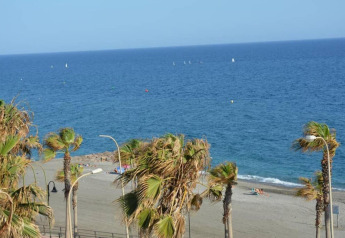 Vista sulla spiaggia e il mare blu dal Tamarit Park Resort 1 THALASSA in Spagna, circondato da palme.