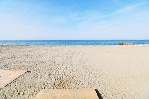 Rustig zandstrand met blauwe zee en heldere lucht bij Tamarit Park Resort 1 THALASSA in Spanje.