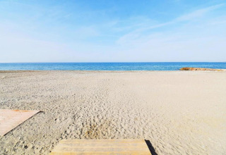 Rustig zandstrand met blauwe zee en heldere lucht bij Tamarit Park Resort 1 THALASSA in Spanje.