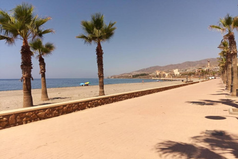 Boulevard met palmbomen aan het strand bij Tamarit Park Resort 1 THALASSA in Spanje, blauwe lucht en zeezicht.