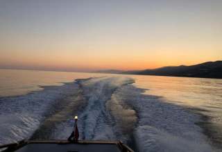 Zonsondergang vanaf een boot bij Tamarit Park Resort 1 THALASSA in Spanje, met waterstrepen achter de boot.