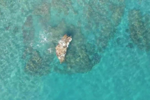 Luchtfoto van helderblauw water en een rots bij Tamarit Park Resort 1 THALASSA in Spanje.