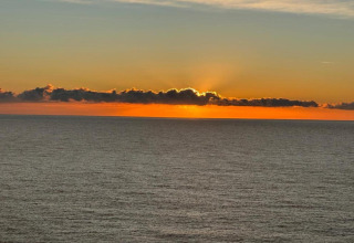Smuk solnedgang over havet, set fra CAMPING INTERPALS- Bungalow Sa Riera i Spanien med orange himmel.