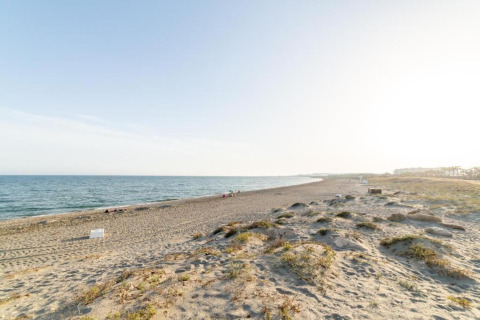 Uitgestrekt zandstrand bij Tamarit Park Resort 1 THALASSA in Spanje, met rustige zee en heldere lucht erboven.