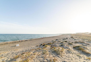 Uitgestrekt zandstrand bij Tamarit Park Resort 1 THALASSA in Spanje, met rustige zee en heldere lucht erboven.