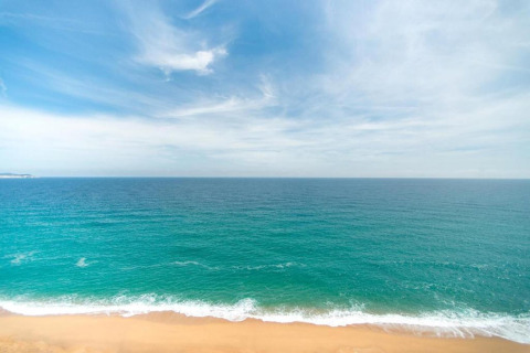 Udsigt over det turkisblå hav og en sandstrand under en blå himmel ved CAMPING INTERPALS i Spanien.