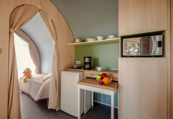 Vue intérieure d'une tente safari avec kitchenette, lit, micro-ondes et bol de fruits en Espagne.