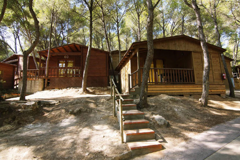 Twee houten bungalows bij Camping Estival Torre de la Mora in Spanje, midden in een bosrijke omgeving.