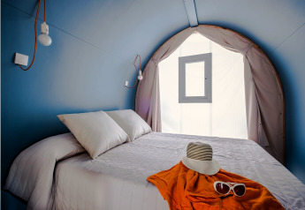 Intérieur de la COCO TENT 4 Pax au Camping Estival Torre de la Mora, Espagne, avec lit et murs bleus courbés.