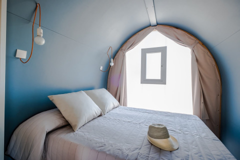 Inde i et COCO TENT soveværelse på Camping Estival Torre de la Mora, Spanien, med seng og hat.