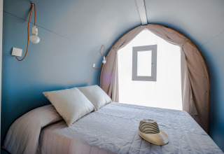 Inde i et COCO TENT soveværelse på Camping Estival Torre de la Mora, Spanien, med seng og hat.
