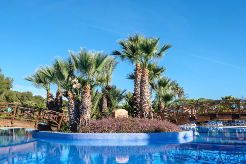 Zwembad met palmbomen en houten bruggen bij Camping Estival Torre de la Mora WOODEN BUNGALOW 5 PAX in Spanje.