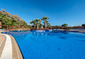 Grande piscine entourée de palmiers et de ponts en bois au Camping Estival Torre de la Mora COCO TENT 4 Pax en Espagne.