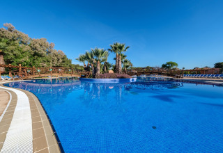 Smuk swimmingpool med palmetræer og træbroer ved Camping Estival Torre de la Mora COCO TENT 4 Pax i Spanien.