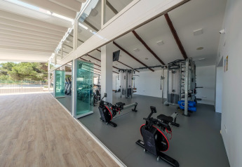 Salle de sport lumineuse et moderne dans un hébergement glamping, grandes fenêtres avec vue sur la nature.