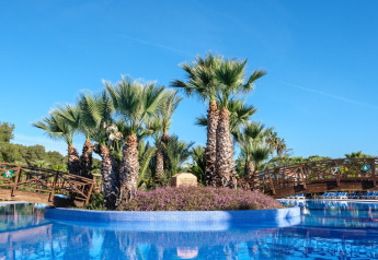 Palmeninsel mit Holzbrücken inmitten eines Pools im Camping Estival Torre de la Mora COCO TENT in Spanien.