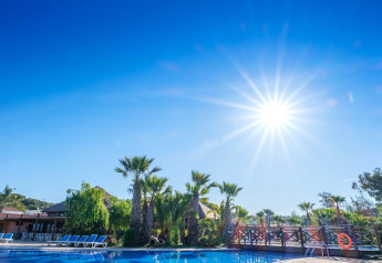 Sonniger Tag am Pool mit Palmen und Liegestühlen im Camping Estival Torre de la Mora COCO TENT 4 Pax in Spanien.