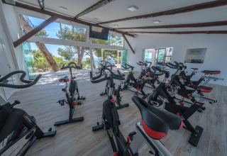Fitnessruimte met hometrainers en grote ramen met zicht op de natuur bij Estival Torre de la Mora.